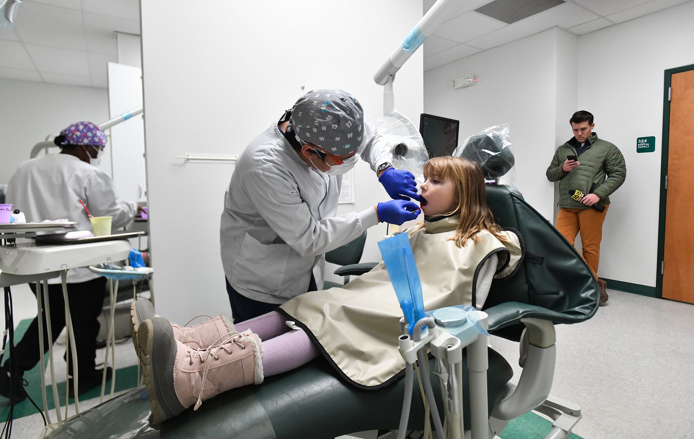 Student dental hygienist John Quizhhpi gives a dental exam to...