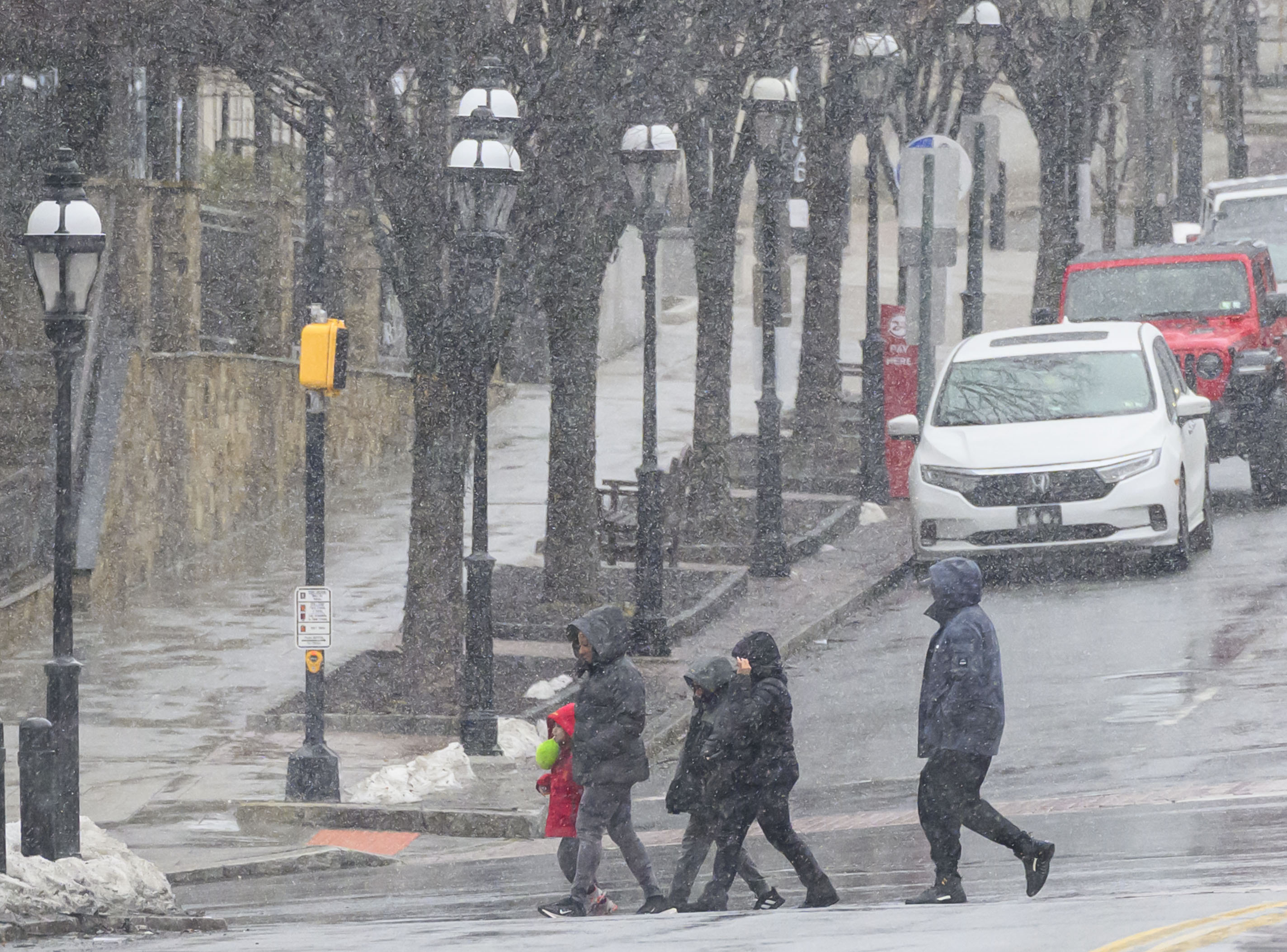 People hurry to cross the street Sunday, Feb. 22, 2026, as the weather changed from rain to flurries in Bethlehem. A winter storm was expected to drop 7-14 inches of snow in the region Sunday into Monday, though the National Weather Service said there was a lot of uncertainty about the total. (April Gamiz/The Morning Call)