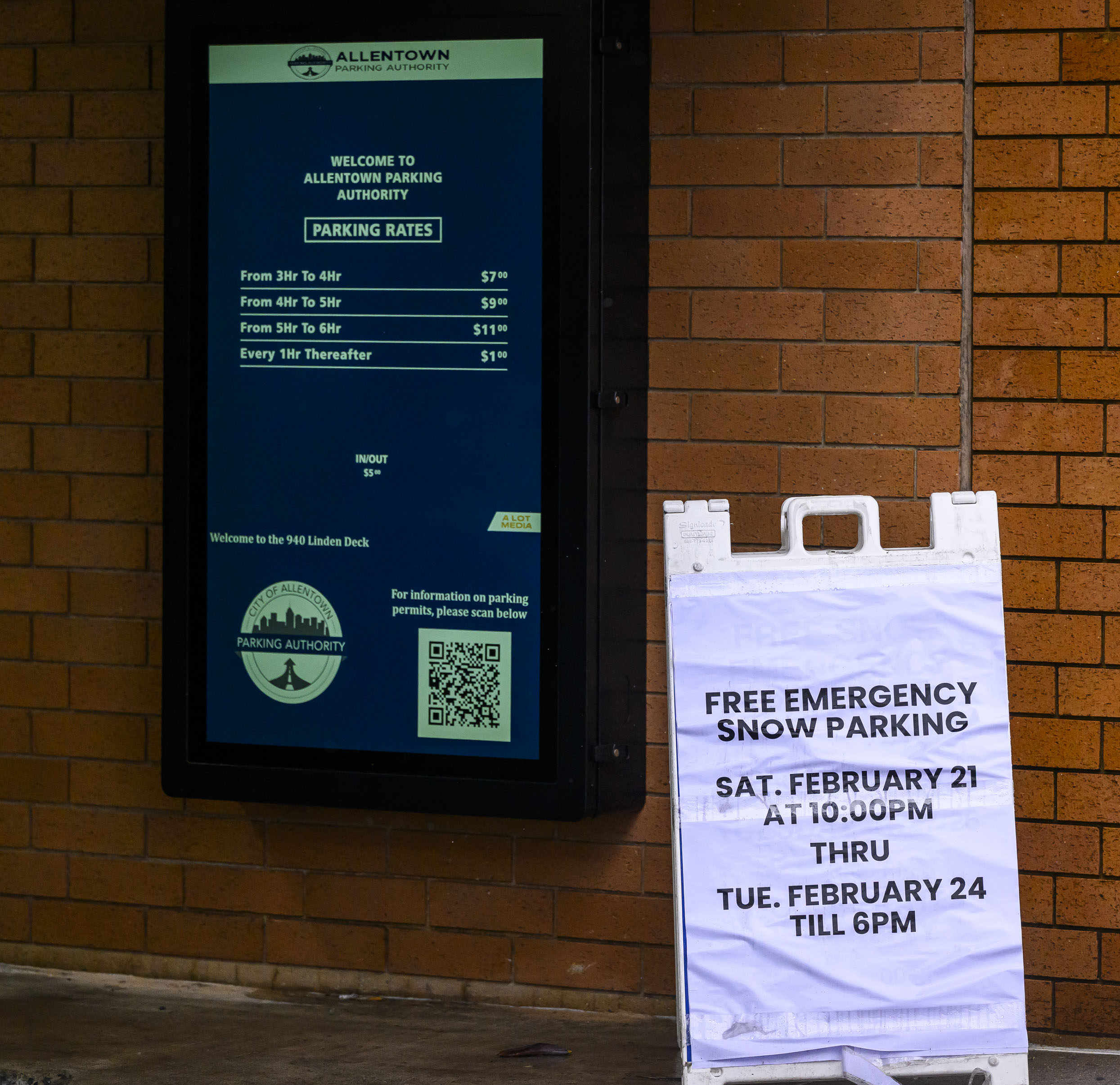 Signs announce free emergency snow parking at parking garages Sunday, Feb. 22, 2026, on Linden Street in Allentown. The city declared an emergency ahead of a winter storm Sunday into Monday that was expected at various points to drop anywhere from 7 to 18 inches of snow in the region. Cars can be parked in city parking garages for free until 6 p.m. Tuesday. (April Gamiz/The Morning Call)