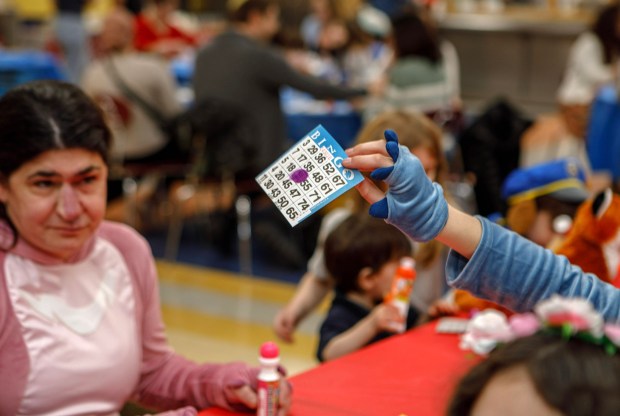 Jamie Gordon-Rodriguez of Allentown looks at her daughter Iris Gordon, 9, holding a Bingo card during a Purim celebration Wednesday, Feb. 25, 2026, at the Jewish Day School of the Lehigh Valley in Allentown. Purim celebrates the biblical story of Esther's deliverance of the Jews in Persia from a massacre plotted by Haman. The holiday, which is marked by the retelling of the Book of Esther, gift giving, meals and costumes, begins this year on Monday evening and continues into Tuesday, March 3, 2026. (Jane Therese/Special to The Morning Call)