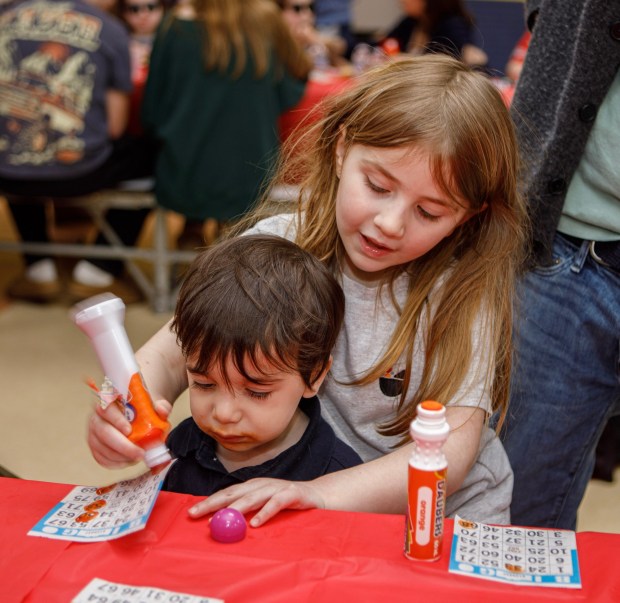 Clementine Toff, 5, of Allentown helps Micah Cohenotis of Allentown at Bingo during a Purim celebration Wednesday, Feb. 25, 2026, at the Jewish Day School of the Lehigh Valley in Allentown. Purim celebrates the biblical story of Esther's deliverance of the Jews in Persia from a massacre plotted by Haman. The holiday, which is marked by the retelling of the Book of Esther, gift giving, meals and costumes, begins this year on Monday evening and continues into Tuesday, March 3, 2026. (Jane Therese/Special to The Morning Call)