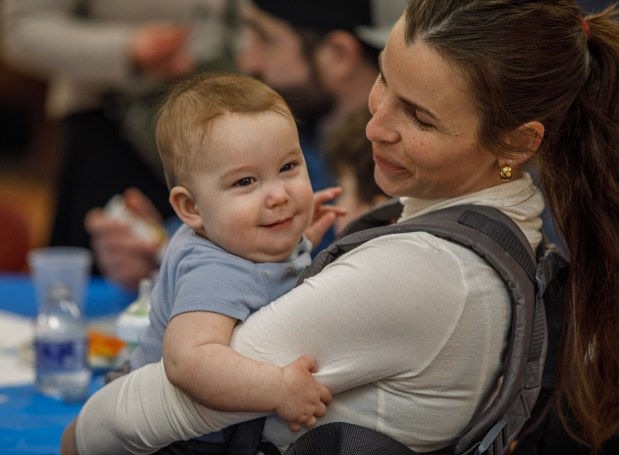 Rachel Loetzbeier of Salisbury Township holds her son Luke, 8 months, during a Purim celebration Wednesday, Feb. 25, 2026, at the Jewish Day School of the Lehigh Valley in Allentown. Purim celebrates the biblical story of Esther's deliverance of the Jews in Persia from a massacre plotted by Haman. The holiday, which is marked by the retelling of the Book of Esther, gift giving, meals and costumes, begins this year on Monday evening and continues into Tuesday, March 3, 2026. (Jane Therese/Special to The Morning Call)