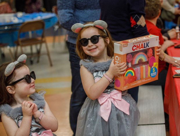 Marlee Meyerson, 3, of Allentown beams at her sister Sophie, 4, holding her prize for Bingo, during a Purim celebration Wednesday, Feb. 25, 2026, at the Jewish Day School of the Lehigh Valley in Allentown. Purim celebrates the biblical story of Esther's deliverance of the Jews in Persia from a massacre plotted by Haman. The holiday, which is marked by the retelling of the Book of Esther, gift giving, meals and costumes, begins this year on Monday evening and continues into Tuesday, March 3, 2026. (Jane Therese/Special to The Morning Call)