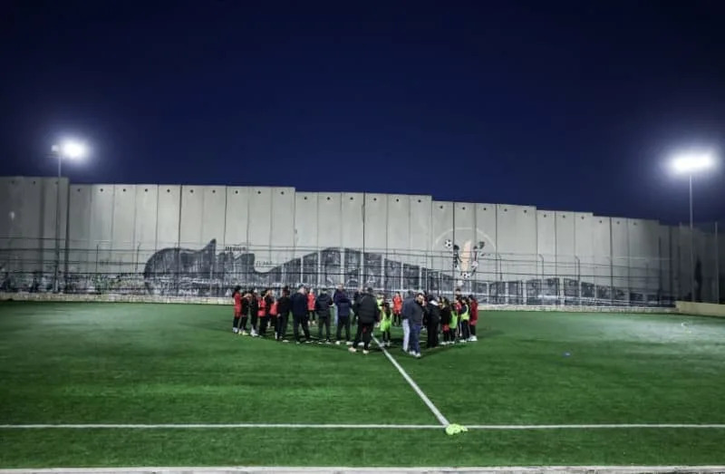 PALESTINIAN YOUTH soccer players play in a field next to the barrier separating Aida refugee camp from Jerusalem near Bethlehem in the West Bank. (credit: AMMAR AWAD/REUTERS)