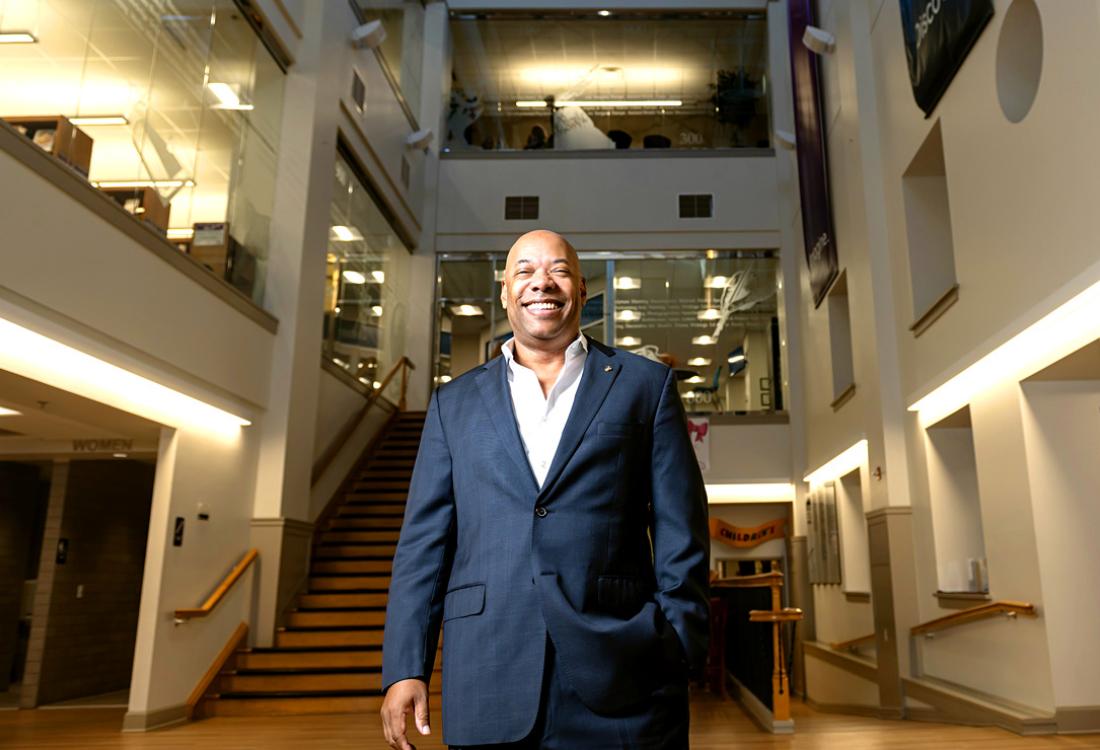 A man poses for a photo while smiling in a building lobby