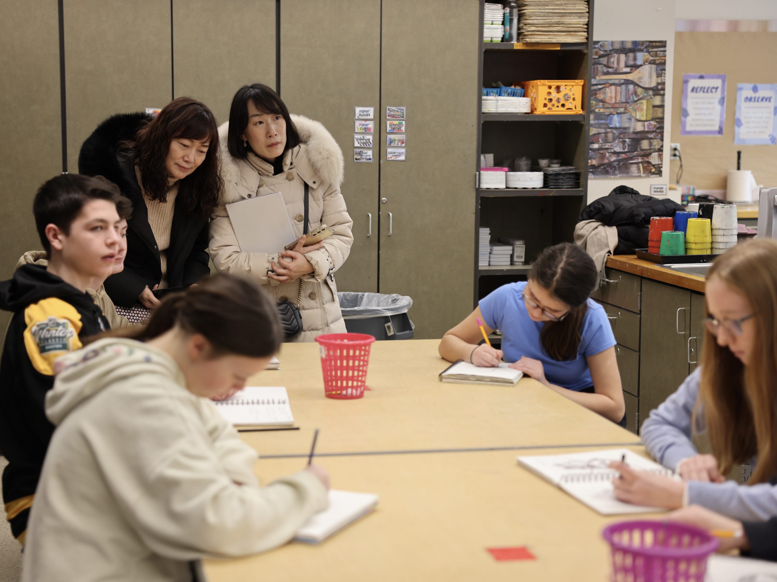 people observe students creating artwork
