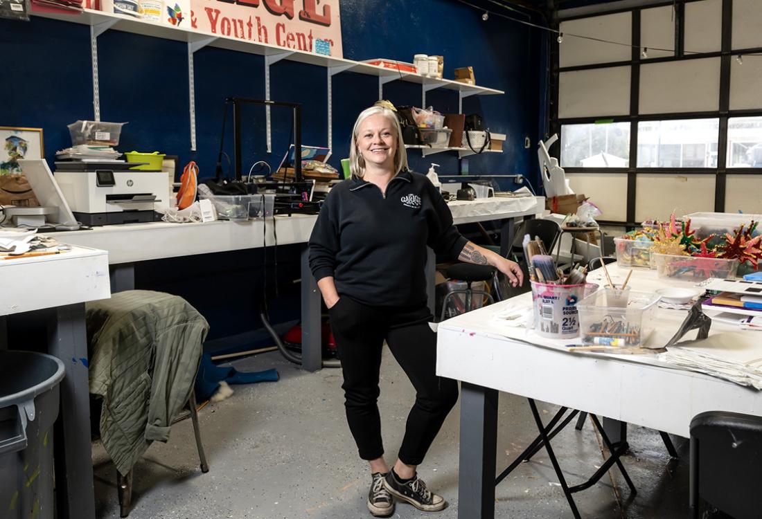 A women poses for a photo amidst a bevy of arts and crafts materials