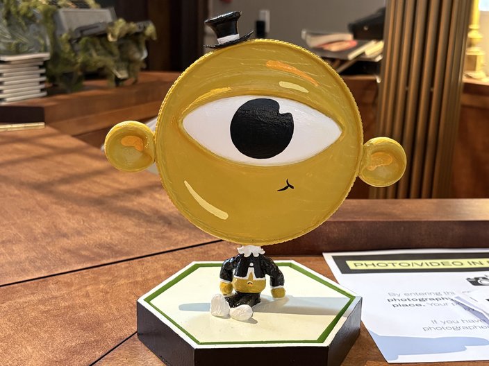 A yellow one-eyed face with a tiny top hat, Mr. P. Balance, sits on the front desk of the Ministry of Awe