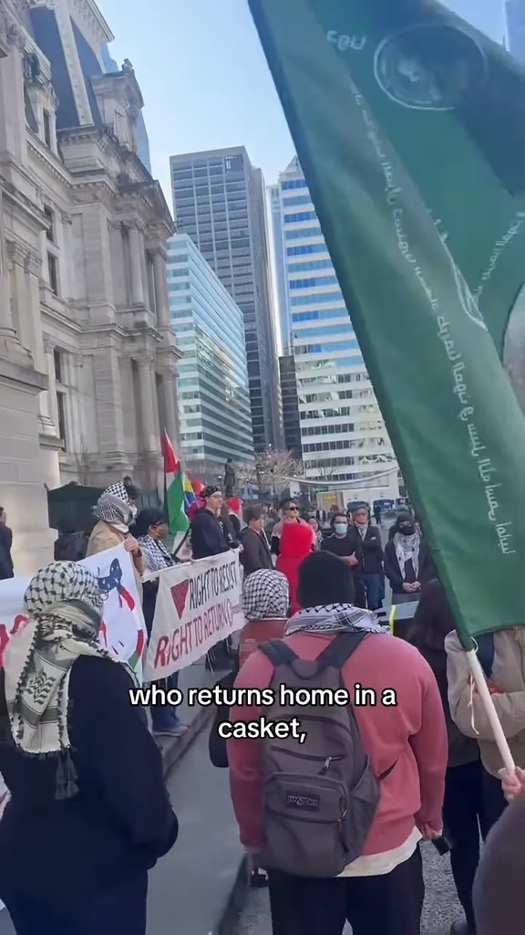 Protestors holding signs and flags, one of which reads "RIGHT TO RETURN," on a city street.
