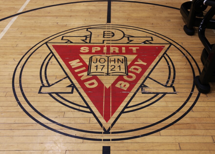 A logo for the YMCA on the floor of a gym.