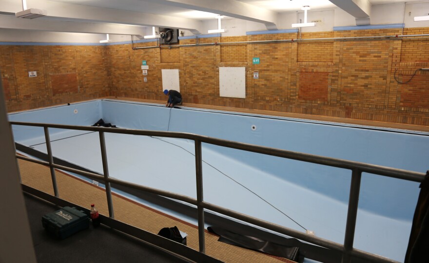 A pool with lining and a man working in the background.