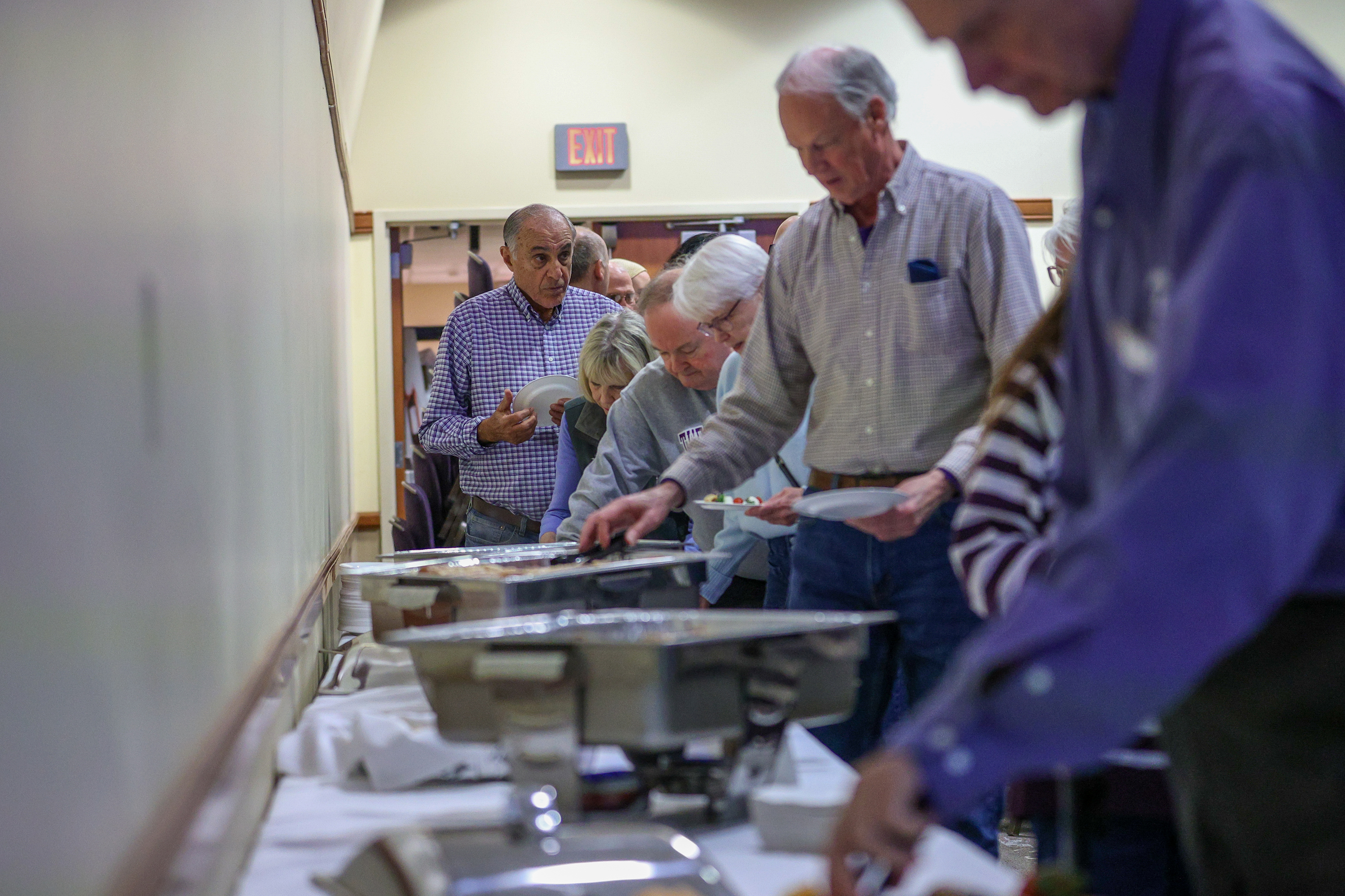 Attendees grab food from a buffet during a watch party...