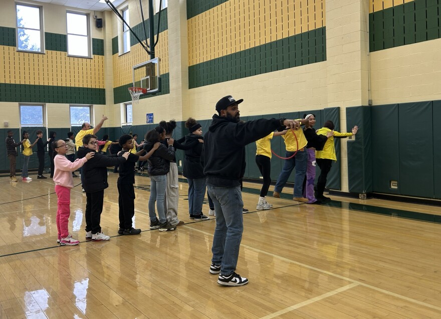 Students stand in a line in a school gymnasium.