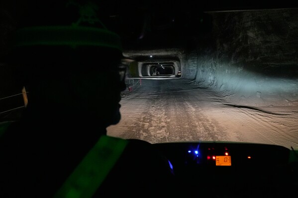 The headlights of the vehicle driven by George Campbell, left, maintenance supervisor, light the way through the tunnels of the Cargill Cleveland salt mine in Whiskey Island, to a current work location, 1,800 feet below the surface of Lake Erie and six miles from the entrance of the mine, in Cleveland, Ohio, Thursday, March 19, 2026. (AP Photo/Sue Ogrocki)