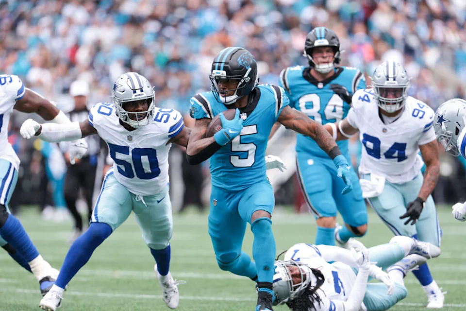 Oct 12, 2025; Charlotte, North Carolina, USA; Carolina Panthers running back Rico Dowdle (5) runs with the ball while getting pressured by Dallas Cowboys linebacker Shemar James (50) during the second half at Bank of America Stadium. Mandatory Credit: Scott Kinser-Imagn Images
