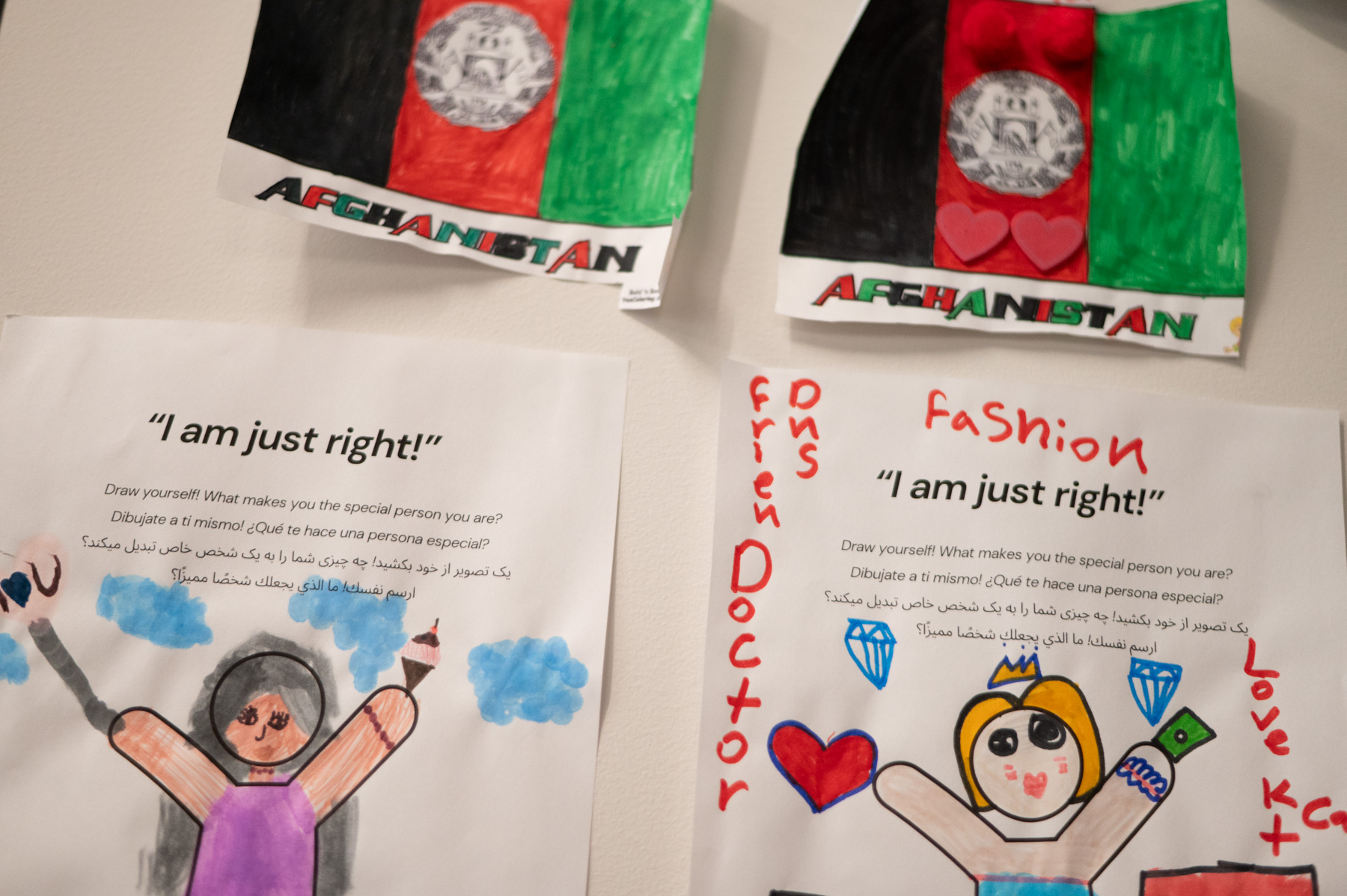 Art made by youth hangs on a wall below hand-drawn Afghanistan flags.