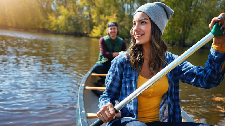 A couple canoeing with trees behind them.
