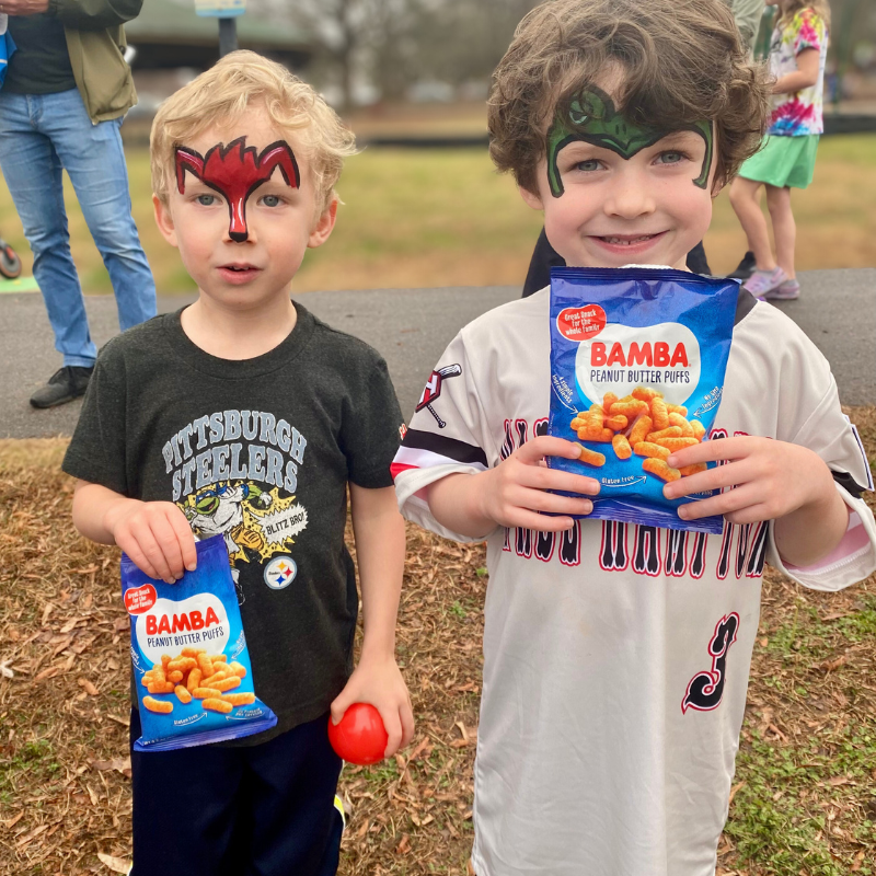 Two little boys holding Bamba bags at an event