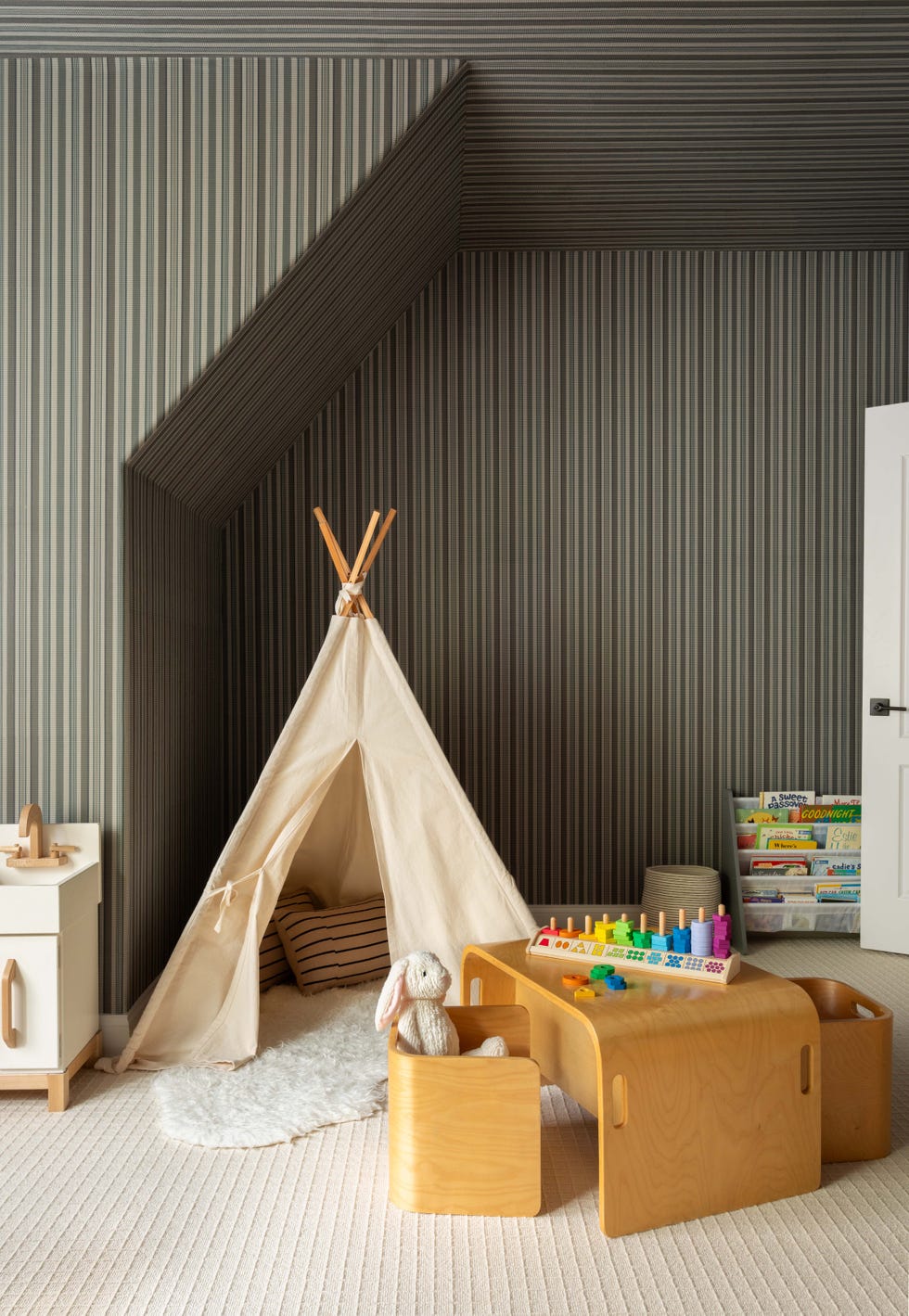 Children's playroom featuring a teepee, toys, and books.