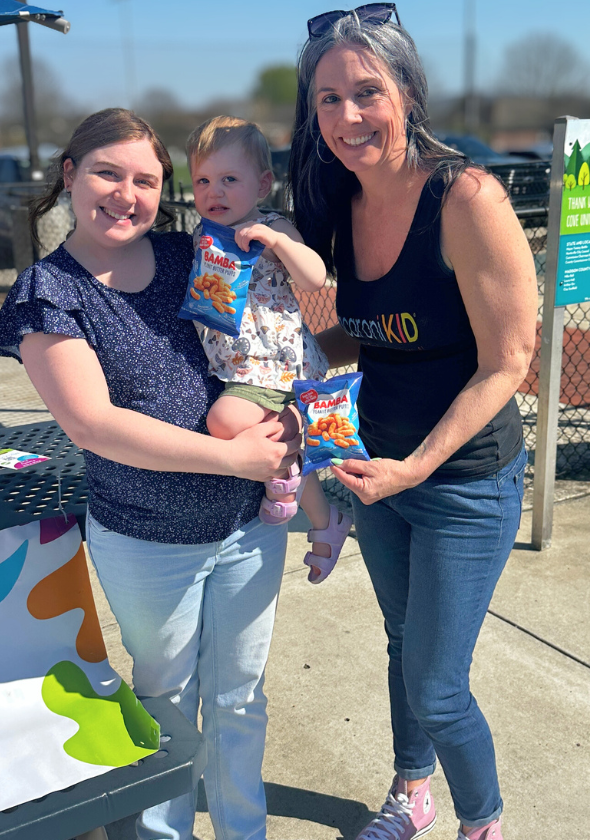 Families trying Bamba snacks at an event attended by Kelly Kerr