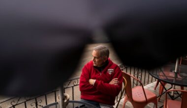 District Attorney Larry Krasner sits with a cup of coffee outside Gleaner’s Cafe in South Philadelphia's Italian Market in March 2024. He is wearing a sweatshirt repping Unite Here, the union that represents hotel, gaming, and food service workers in the city.