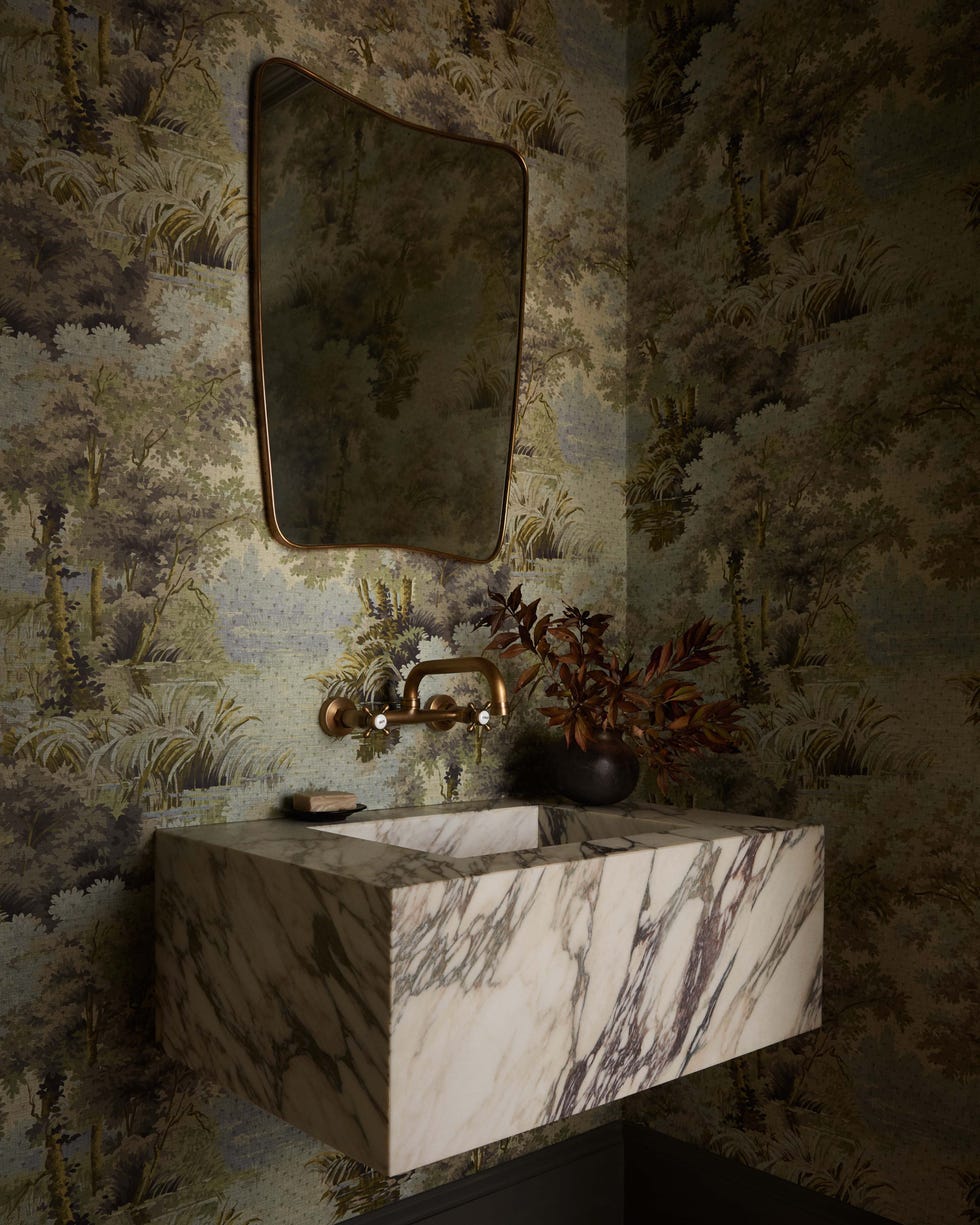 Elegant bathroom sink with a mirror and decorative wallpaper.