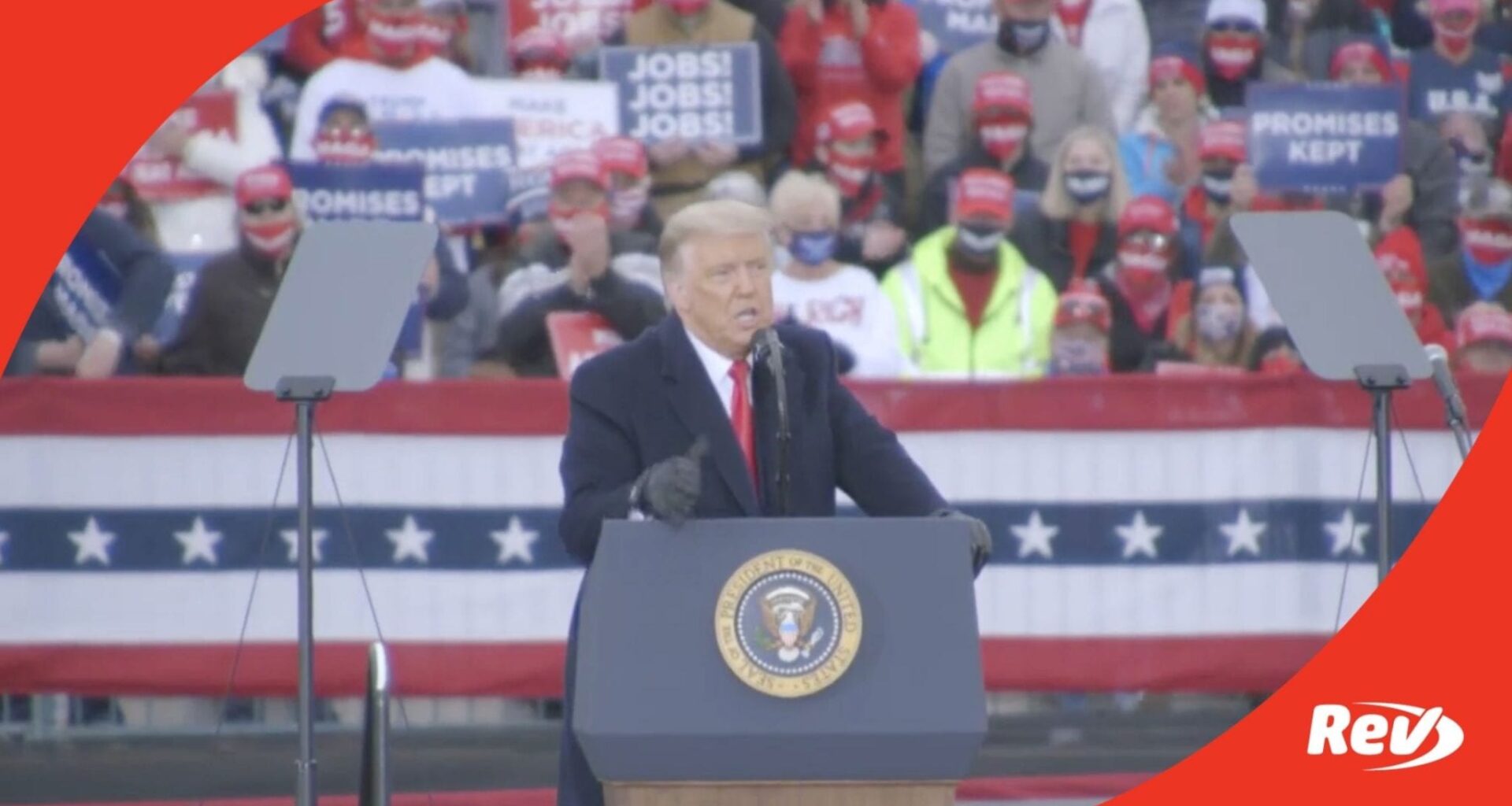 Donald Trump stands at a podium at a rally, with a crowd behind him.