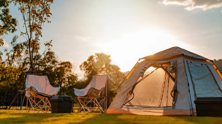 A tent and two chairs at a campsite in the evening light