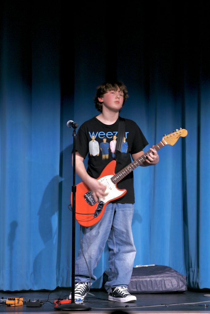 student plays electric guitar