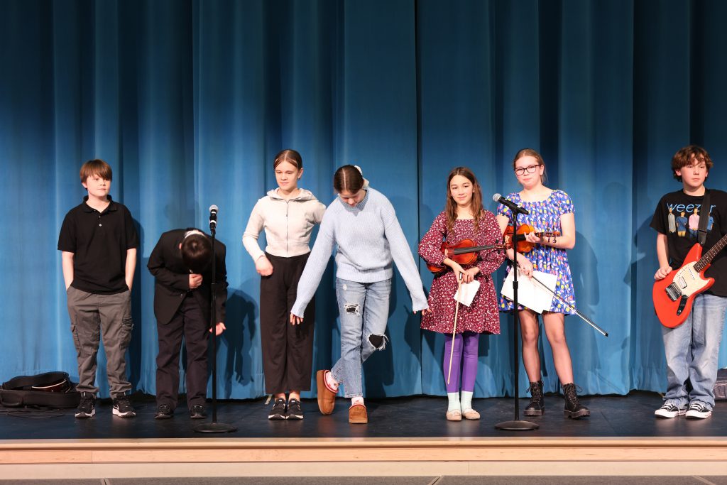 students on stage take a bow