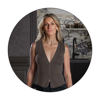 Woman wearing a sleeveless brown cardigan in a stylish kitchen setting.