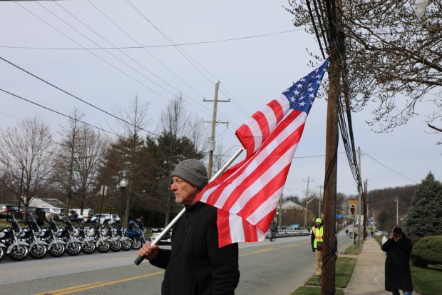 West Bradford resident John McCarter holds up the American flag in the public viewing area, across the parish, during Corporal Timothy O'Connor's funeral mass on Wednesday in Downingtown "We're all Americans. We all want families and happiness and prosperity," he said. "The hatred toward our protectors can't be tolerated." (Jen Samuel Daily Local News)