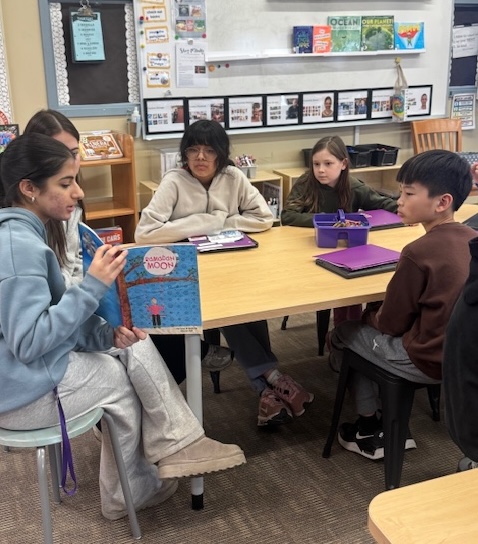high school student reads to elementary students