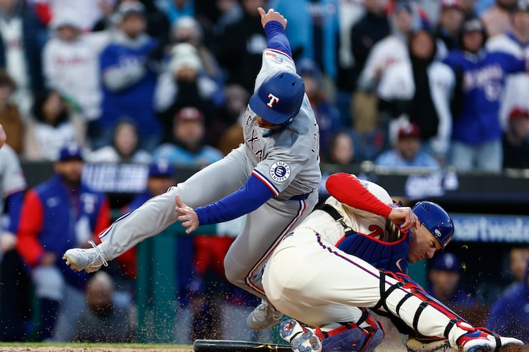 The Rangers' Wyatt Langford collides with Phillies catcher J.T. Realmuto in the 10th inning on Saturday.