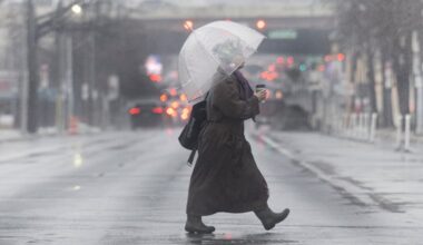 A woman shields herself from the rain with an umbrella as she crosses the street at 8th and Spring Garden Streets in Philadelphia on Thursday, March 5, 2026.