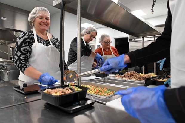 The Helping Harvest Community Kitchen relies on volunteers to package meals for distribution. From left, Angela Berkis of Sinking Spring, Stephanie Gentile from Mohnton and Pollyanne Bonning of Hamburg, all volunteers from FirstEnergy/Met-Ed, prepare Thanksgiving meals in November. (BILL UHRICH/READING EAGLE)