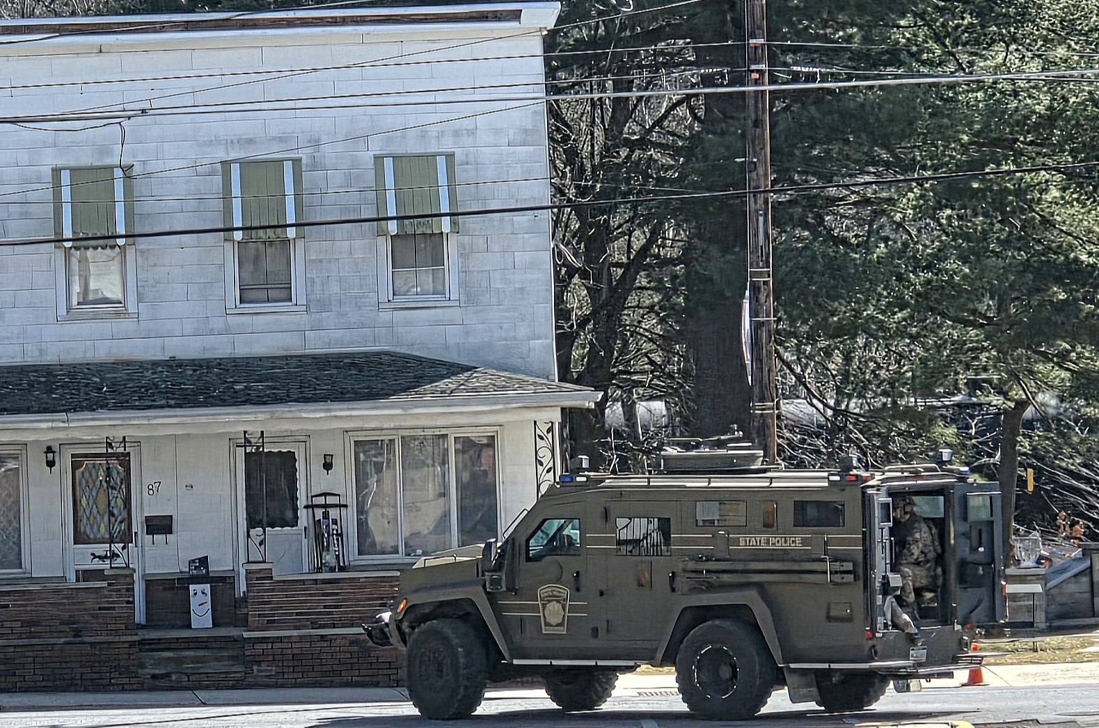 An armored police vehicle parks in front of a residence...