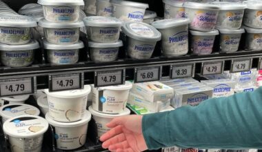 Stuart Dryden reaches for a store-label cream cheese at a grocery store on Wednesday, Feb. 21, 2024, in Arlington, Va. Dryden is aware of big price disparities between branded products and their store-label competitors, which he now favors. (AP Photo/Chris Rugaber)