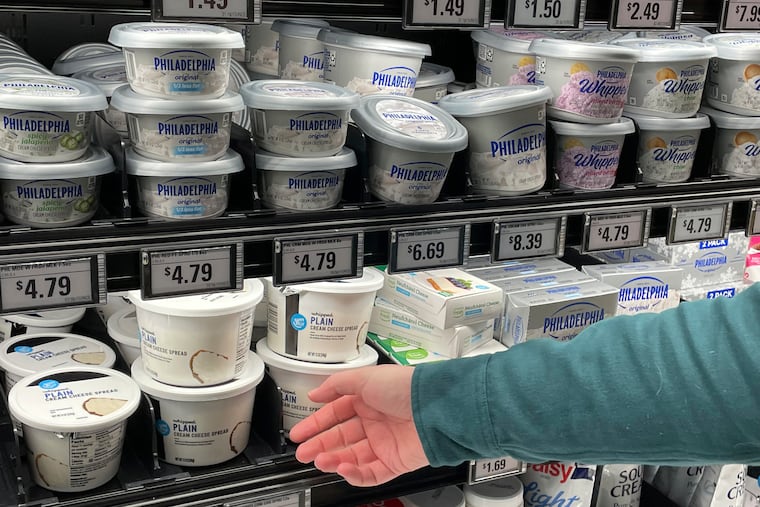 Stuart Dryden reaches for a store-label cream cheese at a grocery store on Wednesday, Feb. 21, 2024, in Arlington, Va. Dryden is aware of big price disparities between branded products and their store-label competitors, which he now favors. (AP Photo/Chris Rugaber)