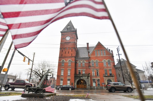 An American flag from the veterans' memorial in Patriot Park frames Carbondale's City Hall Friday, February 20, 2026. (SEAN MCKEAG / STAFF PHOTOGRAPHER)