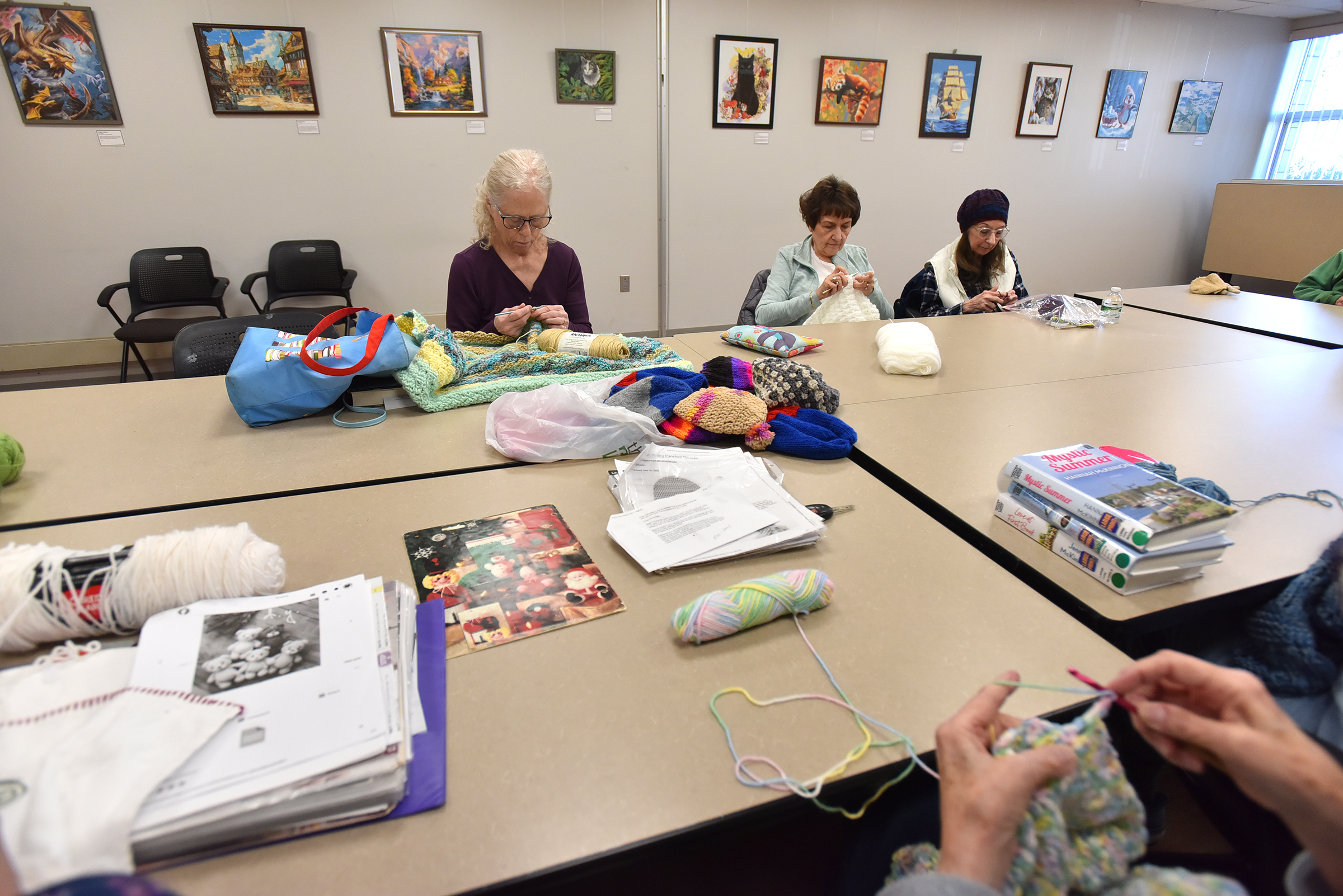 The group “Caring Hands” knits at the Abington Community Library...