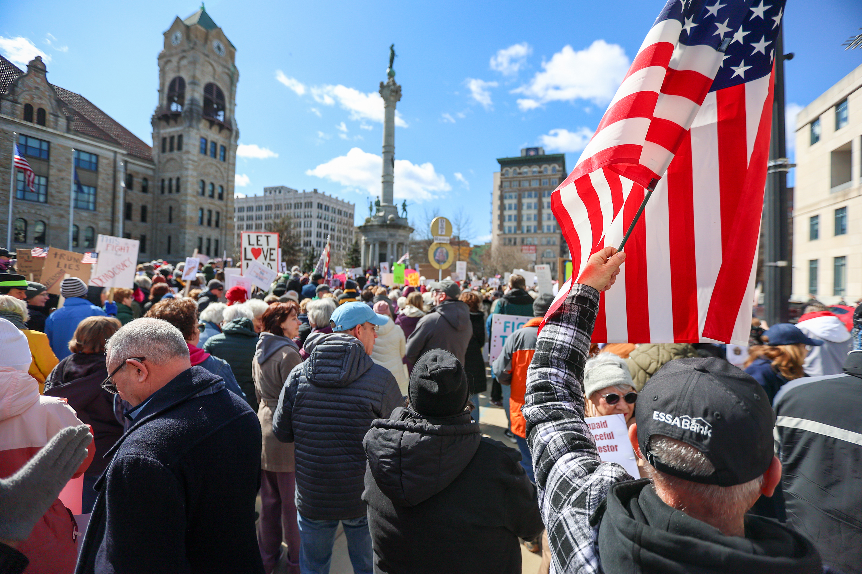 Attendees gather on Courthouse Square and hold their signs during...