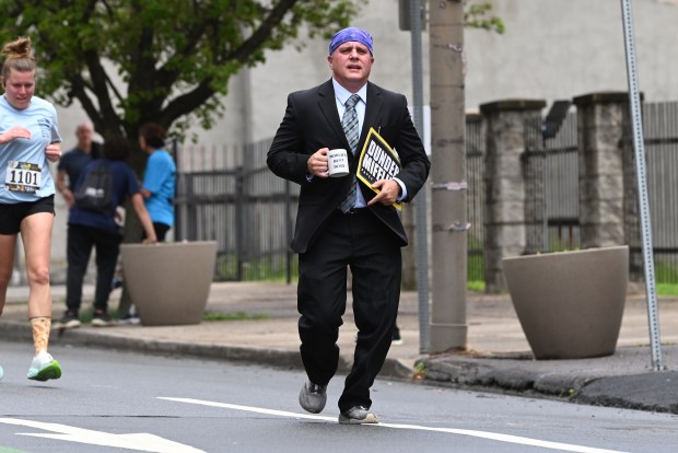 Chris Campion, Scranton, holds a "World's Best Boss" mug during the Office 5K in downtown Scranton on Saturday, May 3, 2025. (REBECCA PARTICKA/STAFF PHOTOGRAPHER)