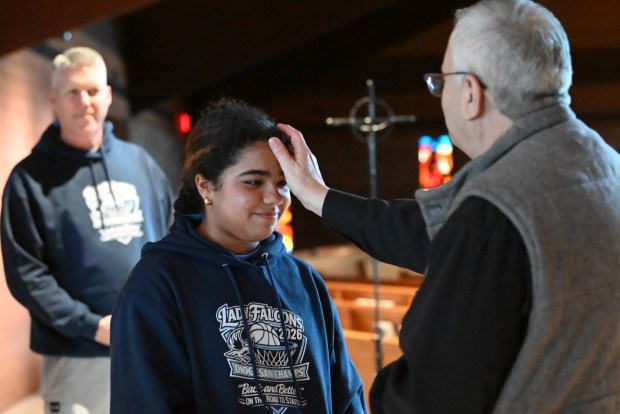 Our Lady of Peace School seventh grader Wilhelmina Walsh receives a blessing from Father John Lapera at Church of Saint Gregory in Clarks Green before heading to the bus with her basketball teammates on Thursday, March 12, 2026. (REBECCA PARTICKA/STAFF PHOTOGRAPHER)