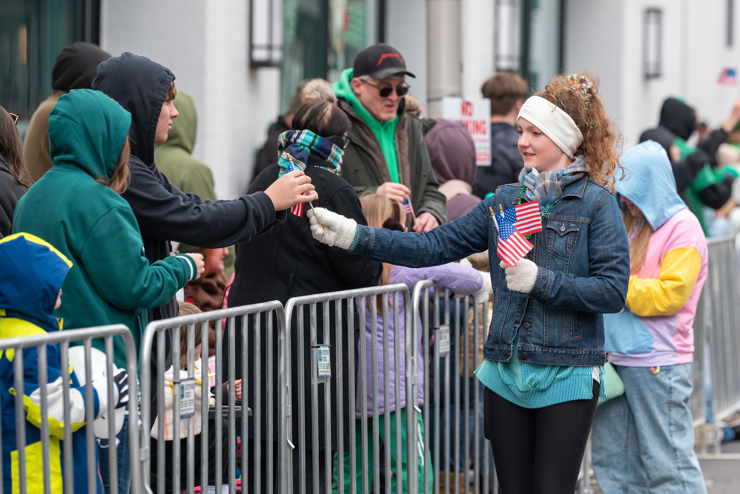 Spectators are handed flags during the St. Patrick’s Parade in...