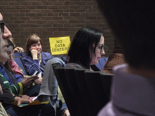 A woman holds up a "NO DATA CENTERS" sign during a public hearing on the Wildcat Ridge Data Center Campus at the Valley View High School in Archbald on Tuesday, March 10, 2026. (FRANK WILKES LESNEFSKY / STAFF PHOTO)