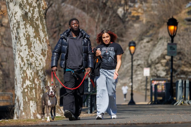From left Milo (dog), Liam Kamara, and Jocilyn Koser walk along Kelly Drive in Philadelphia Friday afternoon.