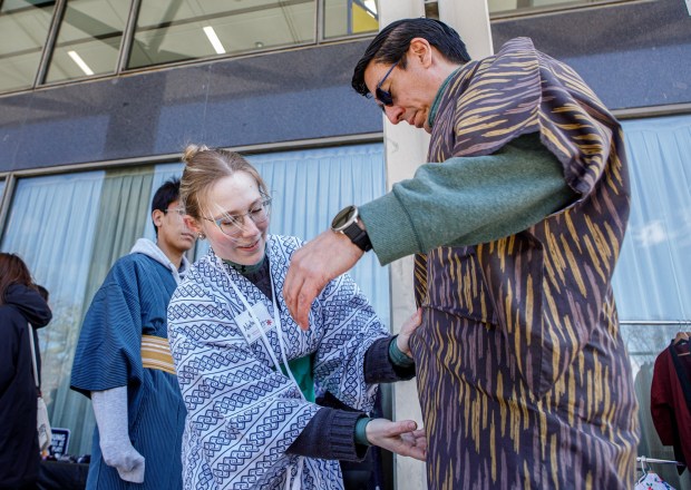 Natalie Sensing of Bethlehem wraps Gino Ximenez of Breinigsville in a yukata during the Bethlehem-Tondabayashi Sister City Commission's annual Cherry Blossom Festival on Saturday, March 28, 2026, at the Garden of Serenity in Bethlehem. The festival featured Japanese music, food, origami and tea ceremonies. (Jane Therese/Special to The Morning Call)