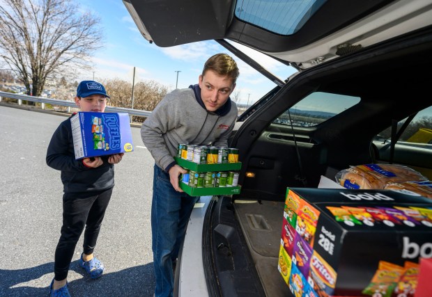 David Noecker and nephew Kandon Noecker, 9, both of New Ringgold, donate nonperishable items during a Fill the Bus donation drive Thursday, March 19, 2026, at Lehigh Valley International Airport. More than 20 carts were filled with donated paper products; toiletries, diapers and other baby products; gift cards; and nonperishable foods and beverages for Transportation Security Administration and Federal Aviation Administration workers at the airport who aren't being paid during the partial federal government shutdown. (April Gamiz/The Morning Call)