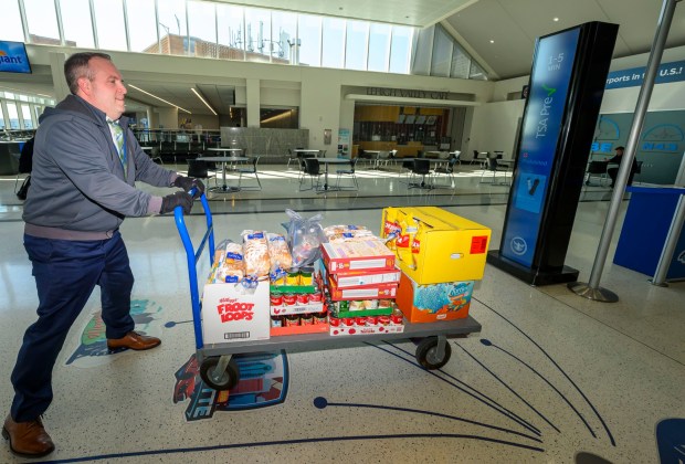 Lehigh-Northampton Airport Authority spokesperson Colin Riccobon pushes a cart toward a Transportation Security Administration area to be scanned then organized during a Fill the Bus donation drive Thursday, March 19, 2026, at Lehigh Valley International Airport. More than 20 carts were filled with donated paper products; toiletries, diapers and other baby products; gift cards; and nonperishable foods and beverages for TSA and Federal Aviation Administration workers at the airport who aren't being paid during the partial federal government shutdown. (April Gamiz/The Morning Call)